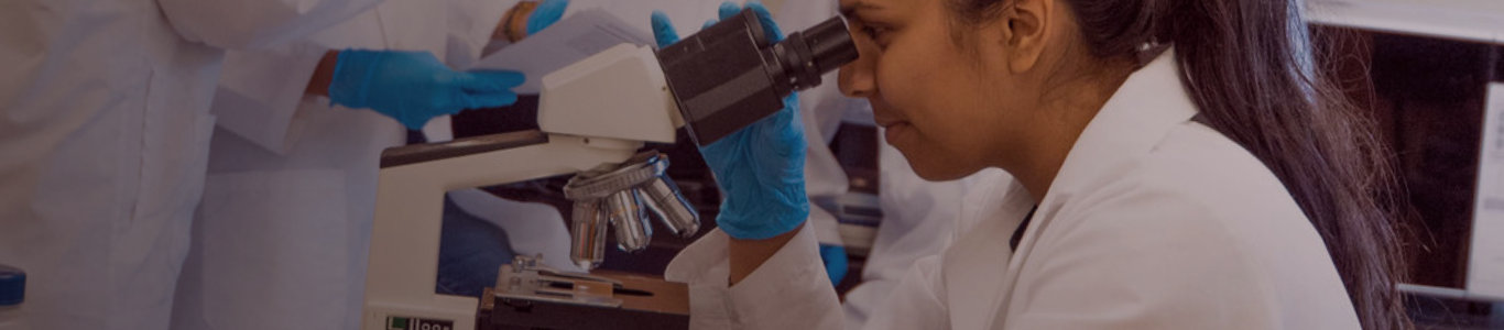 female doctor looking thru a microscope