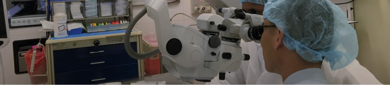 male doctor looking thru a microscope
