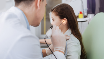 male doctor inspecting a young girls ear